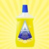 Żółta butelka płynu do mycia podłóg z niebieską nakrętką, na której widnieje napis: "Astonish FLOOR CLEANER Zesty Lemon". Tło jest żółte z promienistym wzorem, a na etykiecie znajduje się również symbol "Vegan" oraz grafika cytryn.