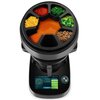 Na zdjęciu widoczny jest wielofunkcyjny robot kuchenny z sześcioma przegródkami na składniki, wypełnionymi różnymi produktami spożywczymi, oraz wyświetlaczem dotykowym z interfejsem użytkownika. Na wyświetlaczu znajduje się tekst: "Tacos veganos con soja 