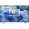 Na zdjęciu widoczny jest telewizor z wyświetlonym na ekranie tekstem: "SAMSUNG Nr 1 NA ŚWIECIE Najczęściej kupowane telewizory od 19 lat" oraz logo "QLED". Tło ekranu przedstawia abstrakcyjne, niebiesko-białe wzory przypominające tekstury lodu i futra.