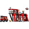 Zestaw LEGO przedstawia remizę strażacką z czerwonym wozem strażackim, budynkiem z numerem "2" oraz figurkami strażaków i psem. Na dachu remizy znajduje się dron, a na ścianie widoczny jest symbol płomienia.