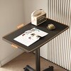 Na zdjęciu znajduje się czarny stolik pod laptopa z wymiarami 60 cm na 40 cm, na którym leży otwarta gazeta, stoi kremowy głośnik z widocznym napisem oraz filiżanka z kawą. Stolik ma podświetlane krawędzie, a w tle widać fragmenty ściany i podłogi.