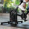 Na zdjęciu znajduje się interaktywny trenażer rowerowy CYCPLUS T2 z zamontowanym rowerem, na którym pedałuje osoba w białych butach i skarpetkach. W tle widoczne są rośliny i duże okno, a na trenażerze widnieje napis "CYCPLUS T2".