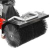 Na zdjęciu widoczna jest spalinowa zamiatarka z dużą, czarną szczotką cylindryczną oraz metalowym uchwytem na górze. Szczotka jest zamontowana na czerwonej podstawie, a w tle widać fragment silnika.