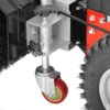 Zbliżenie na mechanizm zamiatarki spalinowej z widocznym czerwonym kółkiem obrotowym, metalowymi elementami konstrukcyjnymi oraz fragmentem dużego, gumowego koła z bieżnikiem. W tle widoczne są czarne szczotki oraz czerwone i srebrne elementy montażowe.