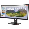 Monitor o zakrzywionym ekranie wyświetla prezentację z dużym napisem "WIND ENERGY" oraz obrazem zielonych wzgórz i miasta. Na podstawie monitora widoczne jest logo "Lenovo".