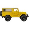 Żółty model samochodu terenowego z czarnymi kołami, przedstawiający szczegółowy design z widocznymi oknami i kołem zapasowym z tyłu. Produkt to "Samochód Hot Wheels Premium Boulevard Toyota Land Cruiser FJ43 JBL25".