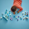 Na zdjęciu widoczne są klocki LEGO z serii DUPLO, przedstawiające elementy zamku oraz postacie z bajki. Wśród klocków znajdują się figurki, różnokolorowe elementy konstrukcyjne oraz akcesoria, ułożone na niebieskim tle.