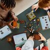 Na zdjęciu widoczne są trzy tablety z wyświetlonymi instrukcjami budowy oraz rozłożone klocki LEGO w różnych kolorach i kształtach. Na stole znajdują się także częściowo zbudowane konstrukcje z klocków LEGO.