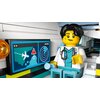 Na zdjęciu znajduje się figurka LEGO ubrana w biały fartuch z nadrukowanym stetoskopem, siedząca w kabinie samolotu. Obok niej widoczny jest ekran z grafiką przedstawiającą samolot, znak ostrzegawczy oraz radar.
