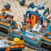 Na zdjęciu znajduje się zestaw klocków LEGO przedstawiający scenę z pociągiem ekspresowym w zimowej scenerii. Widać szczegółowe elementy konstrukcji, takie jak tory, wagoniki oraz figurki postaci w kolorowych strojach, a także rękę manipulującą jednym z e