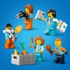 Na zdjęciu znajduje się sześć figurek LEGO w różnych pozach, trzymających akcesoria takie jak aparat, pizza, mapa, kubek, kiełbasa i udko kurczaka. W dolnej części zdjęcia widoczna jest szara skrzynka z marchewką i bananem.