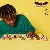 Na zdjęciu znajduje się zestaw figurek LEGO z serii "Spider-Man: Poprzez multiwersum" ustawionych na żółtym tle. W prawym górnym rogu widnieje logo "SPIDER-MAN ACROSS THE SPIDER-VERSE" oraz symbol z napisem "5+".