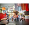 Na zdjęciu znajduje się zestaw klocków LEGO przedstawiający mecha i smoka z serii Ninjago, ustawiony na stole. W tle widoczne są półki z książkami i rośliną, a także kolorowa zasłona.