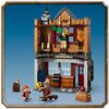 Na zdjęciu znajduje się zestaw LEGO przedstawiający dwupiętrowy budynek z akcesoriami do quidditcha i lodziarnią. W dolnej części widoczne są dwie figurki, beczka oraz miotła, a w górnej części znajdują się różne elementy dekoracyjne, w tym flagi i miotły