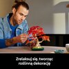 Na zdjęciu widoczny jest model bonsai z czerwonymi liśćmi, zbudowany z klocków LEGO, umieszczony na stole. Na dole zdjęcia znajduje się napis: "Zrelaksuj się, tworząc roślinną dekorację".