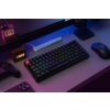 Na zdjęciu znajduje się klawiatura mechaniczna z podświetleniem RGB, obok której leży mysz komputerowa i kontroler do gier. Na biurku widoczny jest również telefon, zegar z wyświetlaczem pokazującym godzinę 13:08 oraz pudełko z napisem "Relaxing BAR".