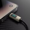 Kabel USB-C - Lightning VEN-DENS z wyświetlaczem LCD podłączony do urządzenia, na wyświetlaczu widoczny jest napis "20W". Urządzenie leży na powierzchni o teksturze przypominającej włókno węglowe.