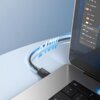 Na zdjęciu widoczny jest czarny kabel USB-C - USB-C podłączony do laptopa, z oznaczeniem "240W" unoszącym się nad kablem. Na ekranie laptopa widać otwarte oprogramowanie z różnymi opcjami edycji obrazu.