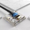 Czarny kabel USB-C - USB-C z plecionym oplotem, zakończony wtykiem z podświetleniem LED, leży na geometrycznej, futurystycznej powierzchni. Na wtyku widoczny jest napis "VEN-DENS".
