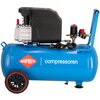Na zdjęciu znajduje się niebieski kompresor olejowy z czarną obudową silnika i czerwonymi elementami, z widocznym logo "AIRPRESS" oraz napisem "compressoren" na zbiorniku. Kompresor ma dwa czarne koła z czerwonymi obręczami i niebieski uchwyt.