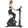 Na zdjęciu znajduje się rower indukcyjny z napisem "TUNTURI" na pionowej kolumnie oraz "Platinum UB30" na obudowie. Osoba siedzi na rowerze, trzymając kierownicę.