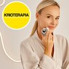 Na zdjęciu widoczna jest osoba trzymająca urządzenie do mezoterapii przy twarzy, ubrana w jasny szlafrok. W lewym górnym rogu znajduje się żółte koło z czarnym napisem "KRIOTERAPIA".