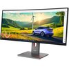 Monitor o zakrzywionym ekranie wyświetla obraz przedstawiający krajobraz z wiatrakami i samochodem na drodze, a na podstawie monitora widoczne jest logo "Lenovo".