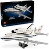 Na zdjęciu znajduje się zestaw LEGO 10360 ICONS Nosiciel Wahadłowców, przedstawiający model samolotu transportującego prom kosmiczny, z widocznym logo NASA i napisem "United States". W tle widoczny jest karton z grafiką zestawu oraz napisami "Shuttle Carr