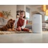 Na zdjęciu znajduje się biały oczyszczacz powietrza marki Philips z widocznym logo, obok którego widnieje oznaczenie wysokości "48.6 cm". W tle widać wnętrze salonu z sofą, poduszkami i rośliną w wazonie.