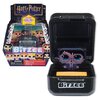 Opakowanie zabawki interaktywnej z motywem Harry'ego Pottera zawiera kolorowe pikselowe postacie z serii, a na górze widnieje napis "Harry Potter" oraz informacja "Try me! Essaye-moi! Probiere mich!". Na otwartym pudełku znajduje się ekran z wyświetlaną p