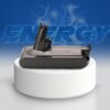 Na zdjęciu znajduje się akumulator w kolorze ciemnoszarym, umieszczony na białym, okrągłym postumencie. W tle widoczny jest napis "ENERGY" na niebieskim tle z efektem błyskawic.