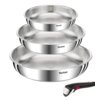 Na zdjęciu widoczne są trzy metalowe patelnie ułożone jedna na drugiej, każda z logo "Tefal" na boku, oraz odłączany uchwyt z czarnym wykończeniem i czerwonym przyciskiem. Patelnie mają błyszczącą powierzchnię, a uchwyt jest umieszczony obok nich.