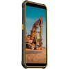 Smartfon z pomarańczową obudową i czarnymi elementami, wyświetlający na ekranie obraz koparki na tle nieba. Na bocznej krawędzi urządzenia widoczne są przyciski oraz tekstura zapewniająca lepszy chwyt.