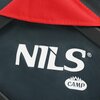 Zbliżenie na fragment materiału wózka turystycznego, na którym widoczne jest logo "NILS CAMP" w kolorze białym. Tło jest ciemne, a w górnej części zdjęcia znajduje się czerwony element materiału.