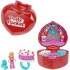 Czerwone, brokatowe pudełko w kształcie serca z napisem "Polly Pocket" zawiera kolorową scenę z balonami i dekoracjami oraz miniaturowe akcesoria, takie jak tort, figurka lalki i niebieski miś. Wnętrze pudełka jest ozdobione motywami serc i gwiazd.