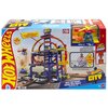 Opakowanie zabawki "Tor Hot Wheels Mega Garaż Gigapętla + auto JBM74" przedstawia kolorowy garaż z pętlą i samochodzikami, z widocznymi napisami: "Hot Wheels City", "Mega Loop Garage", "65cm/2ft+", oraz "Adult assembly required". W prawym górnym rogu znaj