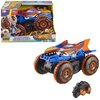 Zdalnie sterowany samochód Hot Wheels Monster Trucks Shark Wspinacz JFR39 jest zaprezentowany w kolorowym opakowaniu z widocznym logo "Hot Wheels Monster Trucks". Na dużych oponach pojazdu widnieje napis "Hot Wheels", a obok znajduje się czarny pilot z po
