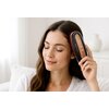 Osoba używa wielofunkcyjnego grzebienia na porost włosów BEAUTIFLY Laserboost Pro Dark, trzymając go przy głowie. Na urządzeniu widoczny jest napis "BEAUTIFLY".