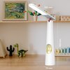 Na zdjęciu znajduje się biała lampka biurkowa o nazwie "FOREVER LIGHT Pure FLB-150 Elena Biały" z wymiarami 350 mm długości, 300 mm wysokości i 70 mm szerokości, ustawiona na drewnianym blacie. W tle widoczne są kolorowe zabawki, obraz w ramce oraz drewni