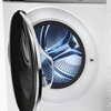 Zdjęcie przedstawia pralkę z otwartymi drzwiami, ukazującą wnętrze bębna. Bęben jest metaliczny, z widocznymi otworami i błyszczącą powierzchnią.
