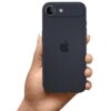 Na zdjęciu widać dłoń trzymającą czarny smartfon z logo w kształcie nadgryzionego jabłka na tylnej obudowie. W górnym rogu urządzenia znajduje się aparat z przezroczystą nakładką ochronną na obiektyw.