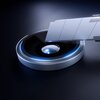 Srebrna nakładka na obiektyw z niebieskim podświetleniem, obok której znajduje się metalowe ostrze. Produkt to "Nakładka na obiektyw 3MK Lens Protection Pro do Apple iPhone 17 Air Srebrny".
