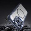 Niebieskie etui na telefon z widocznym wzorem przypominającym włókno węglowe oraz okrągłym oznaczeniem MagSafe, leży na tle ciemnych, rozproszonych kawałków materiału. Etui posiada wycięcia na aparat z trzema obiektywami.