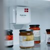 Wnętrze lodówki z widocznym systemem "Cold Air Flow" oraz kilkoma słoikami z przetworami na półce. Na urządzeniu znajduje się czerwone logo z czterema kwadratami.