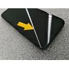 Czarny smartfon leży na szarej, teksturowanej powierzchni, z żółtą strzałką umieszczoną na jego ekranie. Na ekranie odbijają się jasne, liniowe źródła światła.