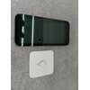 Na zdjęciu widać smartfon z dużym, ciemnym ekranem leżący na szarej powierzchni. Obok znajduje się biała karta z metalowym kluczykiem do otwierania tacki na kartę SIM.