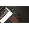Na zdjęciu znajduje się otwarty laptop, obok którego leży czarny telefon z wyświetlaczem pokazującym godzinę 12:46 oraz ikonami zasięgu i baterii. Obok telefonu znajduje się brązowy notes oraz czarny kubek z napojem.