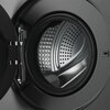 Zdjęcie przedstawia otwartą pralkę z widocznym bębnem wewnętrznym. Bęben ma metaliczną powierzchnię z otworami i charakterystycznym wzorem, a drzwi pralki są uchylone, ukazując zawiasy.