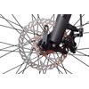 Zbliżenie na tarczę hamulcową roweru górskiego z widocznym mechanizmem hamulcowym i szprychami koła. Na tarczy znajduje się napis "Shimano", a całość jest utrzymana w czarno-srebrnej kolorystyce.