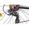 Zbliżenie na mechanizm przerzutki rowerowej z widocznym napisem "Shimano Tourney" oraz zębatki z łańcuchem. W tle widać szprychy koła oraz fragment odblasku w kolorze pomarańczowym.